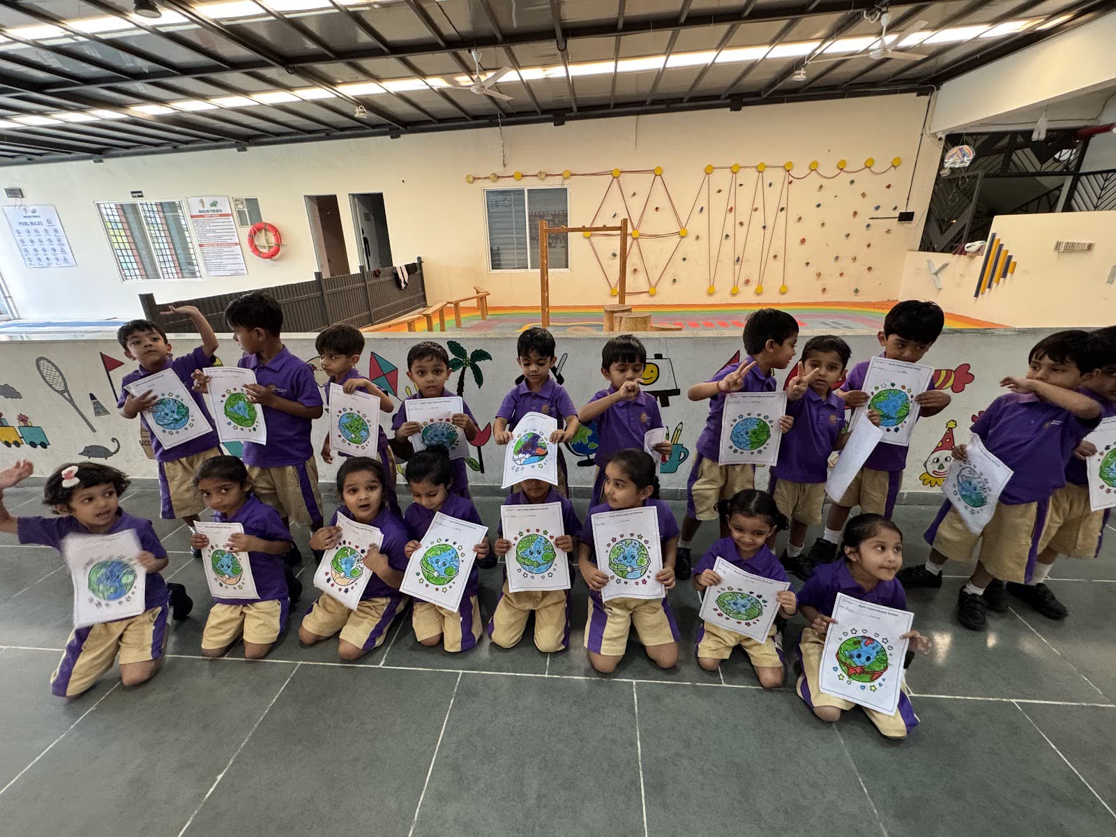 Pre-primary children holding up their artwork in the activity hall