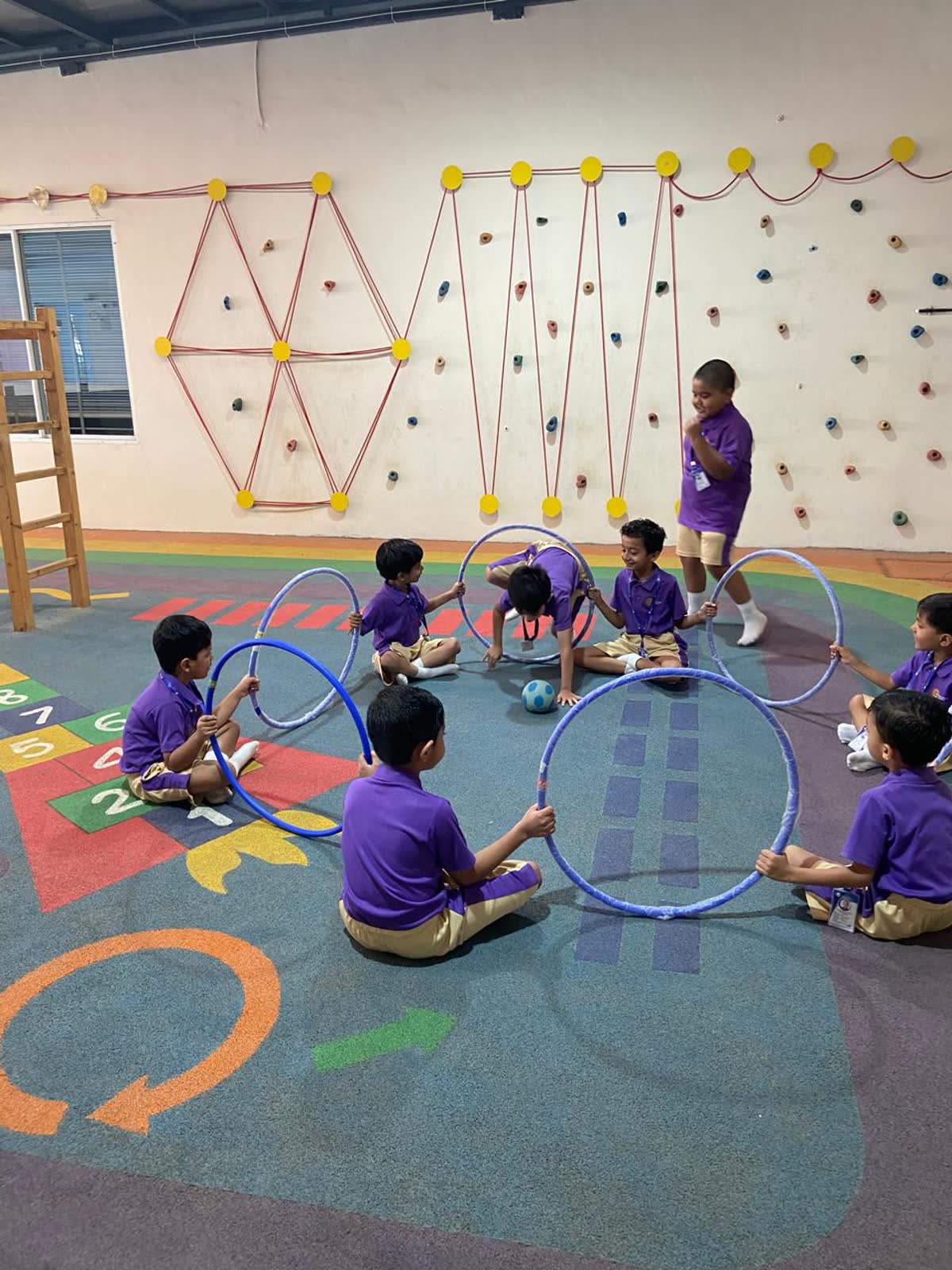 Children playing with hoops beside the climbing wall in the play area