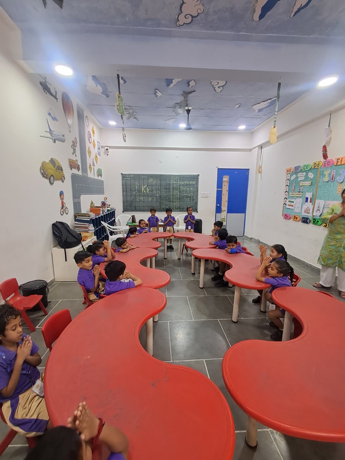 Pre-primary classroom with curved red tables and children at work