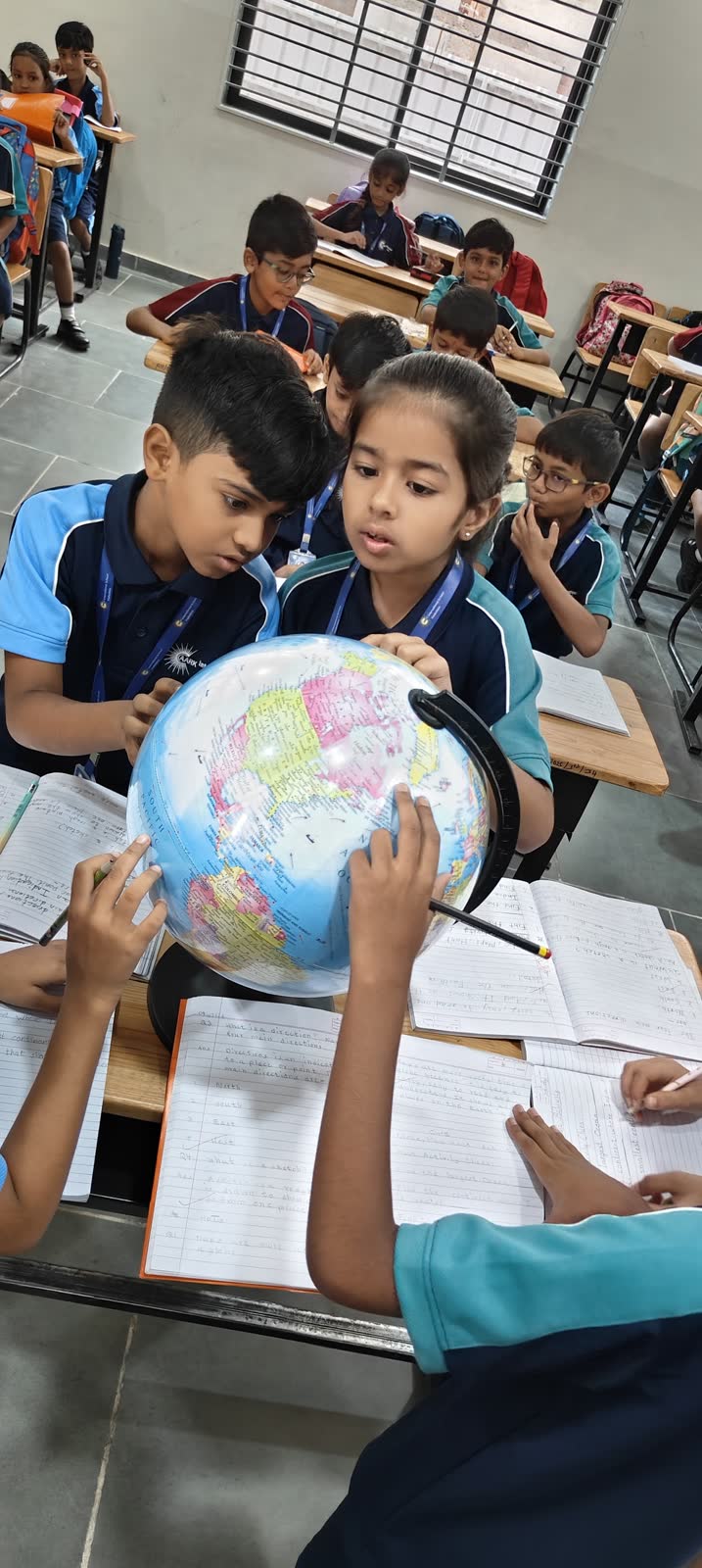 AARK students gathered around a globe, pointing out places during a geography lesson