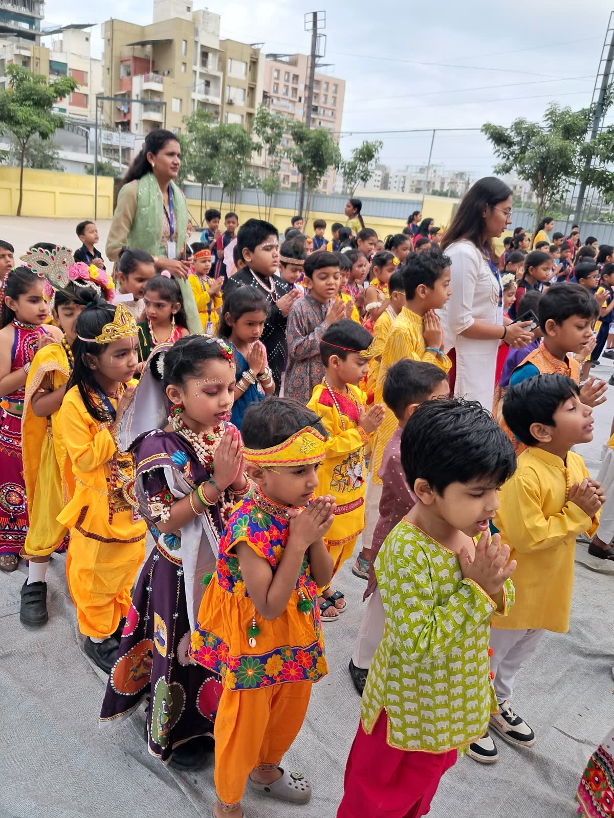 Young AARK students in colourful festival costumes greeting with folded hands