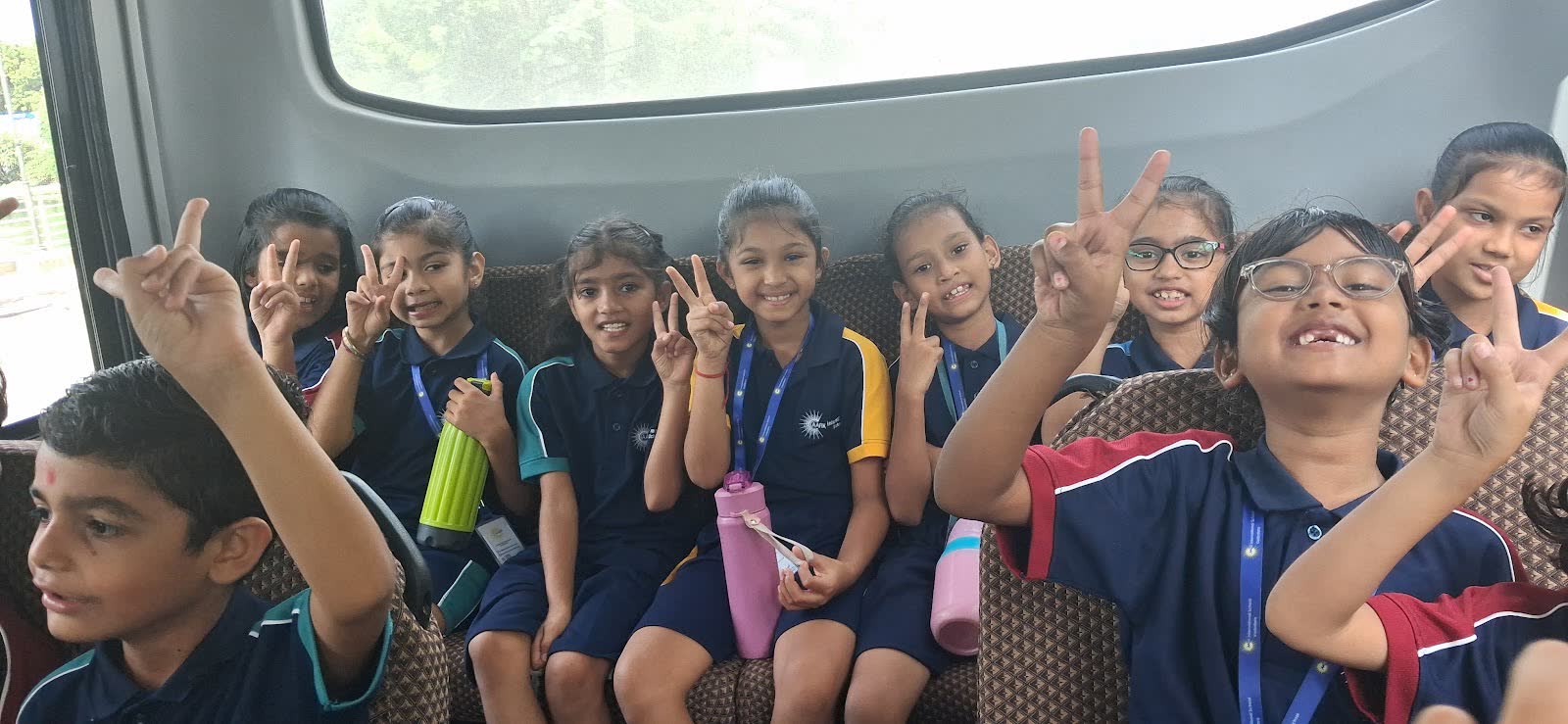 AARK students on a bus showing victory signs on a school trip
