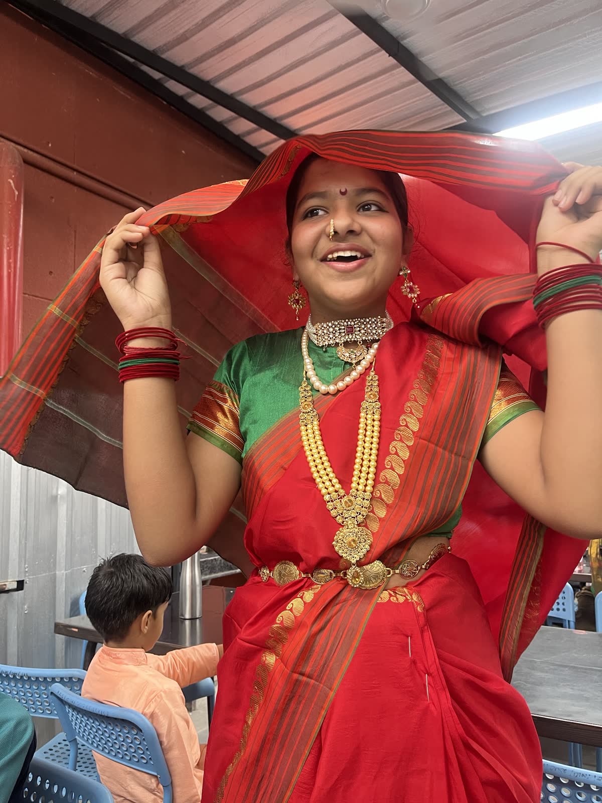 A smiling AARK student in a red traditional saree and jewellery