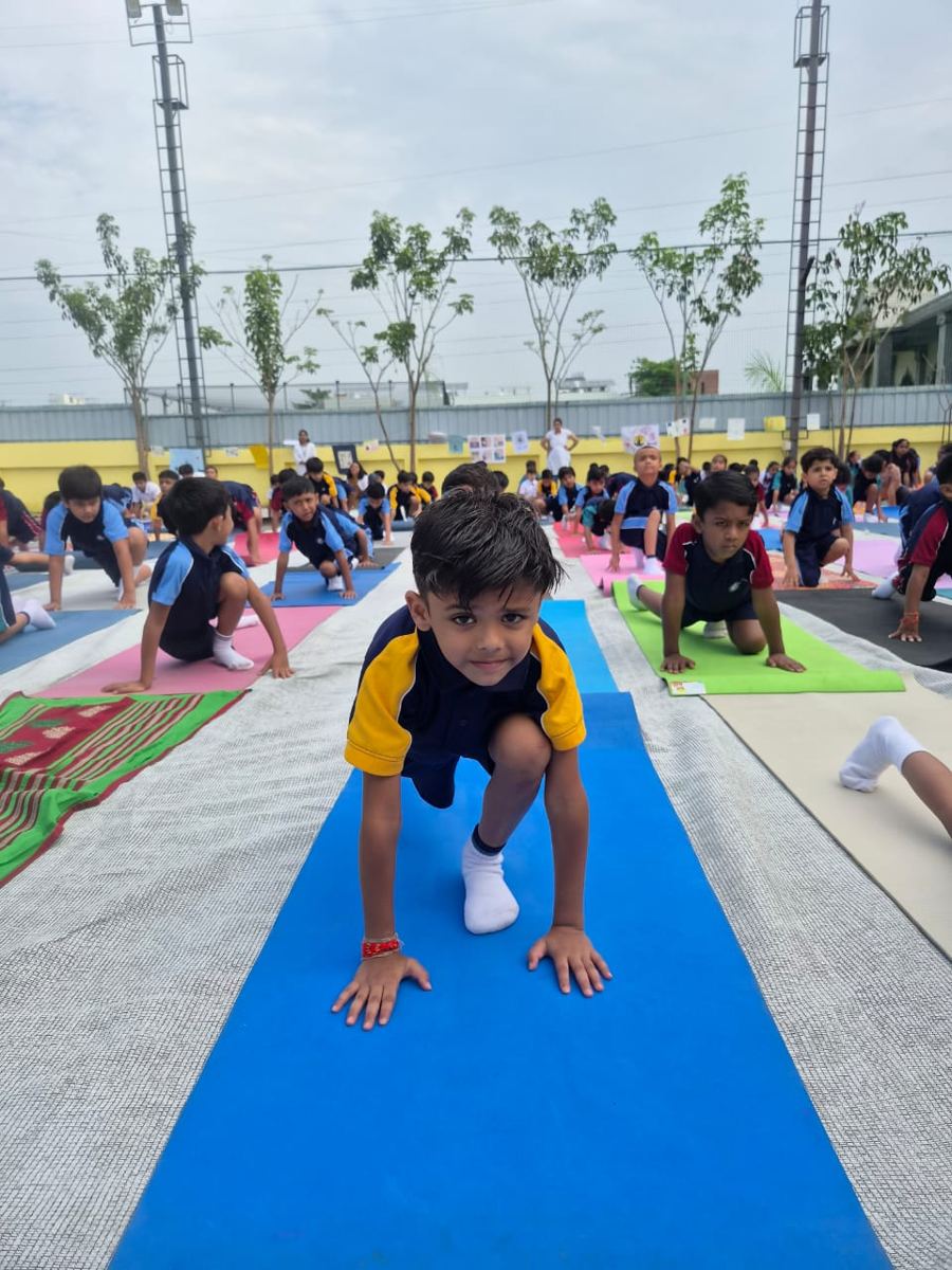 A young AARK student doing a yoga pose on a mat in the school ground