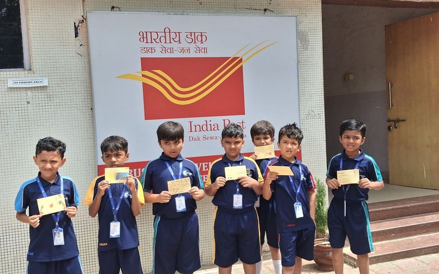 Young AARK students holding postcards outside the post office on a class visit