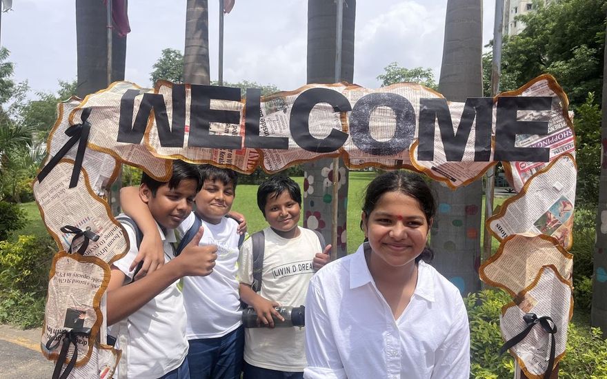 Senior AARK students smiling beside a welcome arch