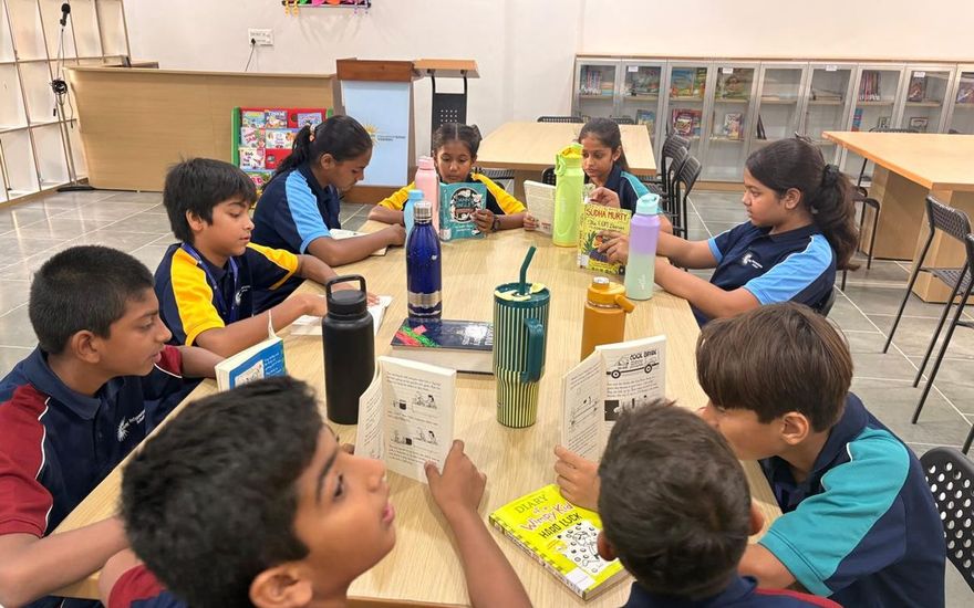 Primary students around a table with their books and project work