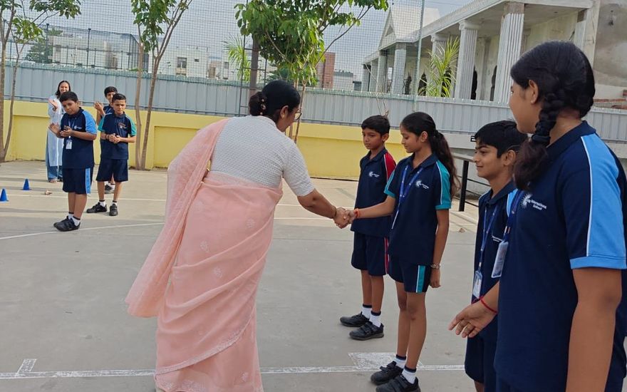 A teacher greeting older AARK students with a handshake
