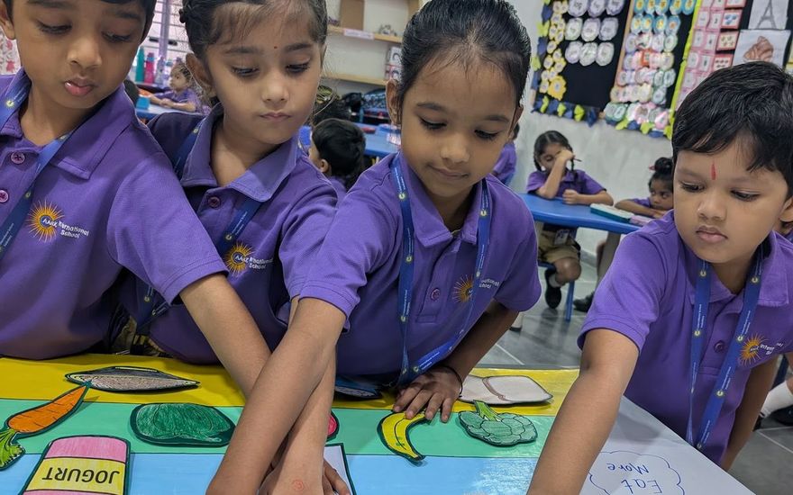 Kindergarten children pointing at pictures on a colourful activity mat